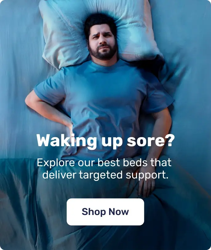 A person lying on a bed with text asking about waking up sore and promoting mattresses that offer targeted support for aches & pains.