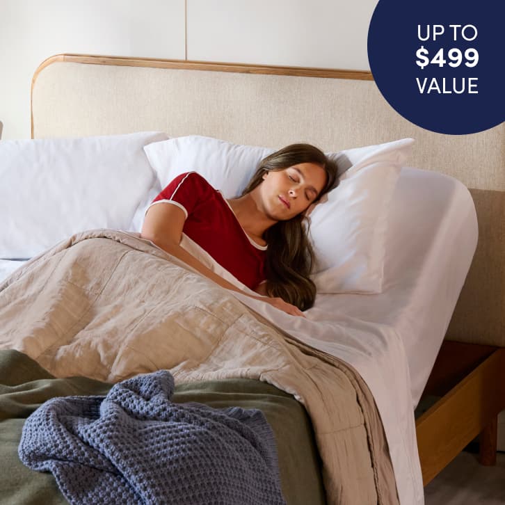 Cozy bedroom scene featuring a person reclining on a bed with an adjustable base, promoting a free adjustable base with qualifying purchase.